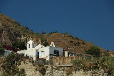 House on mountain against clear blue sky