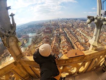 High angle view of man looking at cityscape while standing in balcony