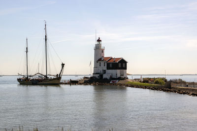 Sailboats in sea by buildings against sky