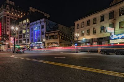 Light trails on city street by buildings at night