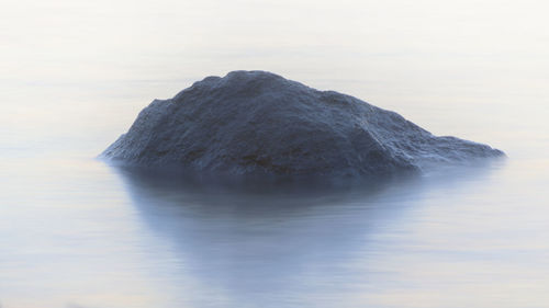 Rock formation in sea against sky
