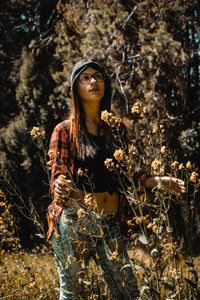 Young woman standing by tree in forest