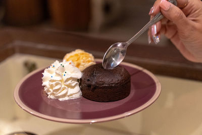 Midsection of person holding ice cream on table