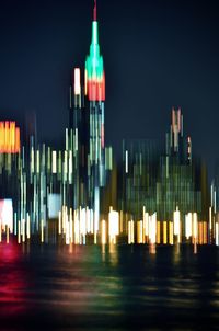 Illuminated modern city against sky at night