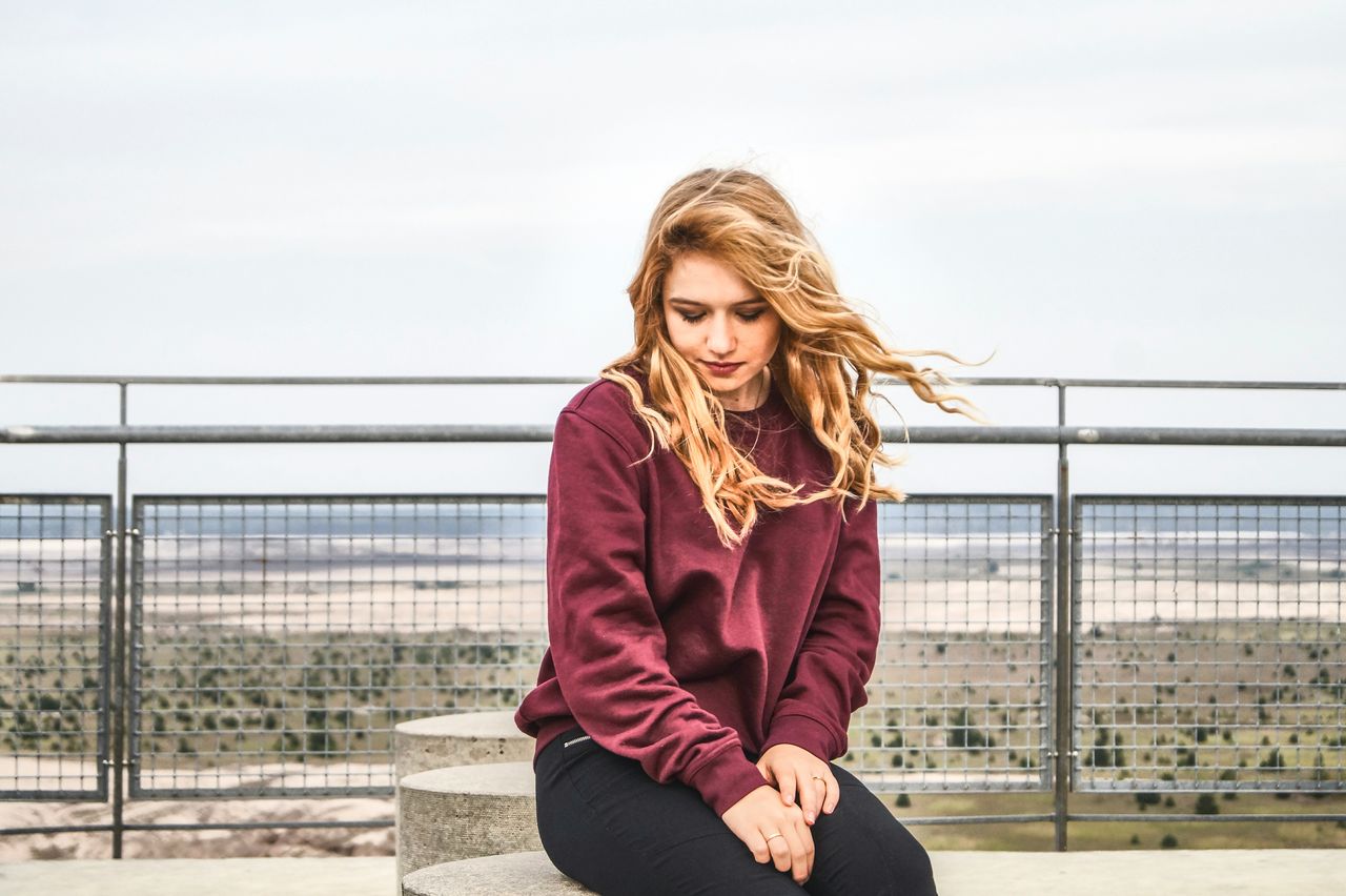 PORTRAIT OF SMILING YOUNG WOMAN AGAINST SKY