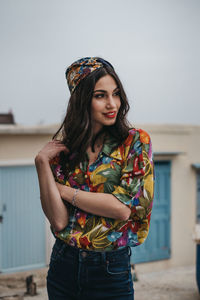 Portrait of beautiful young woman standing against wall