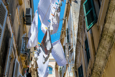 Low angle view of clothes drying on clothesline amidst buildings