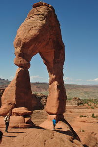 Men against rock formation in sunny day