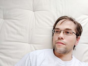 Young man in glasses laying on bare matress