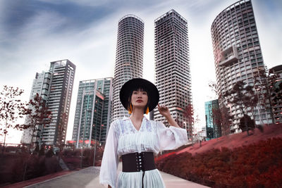 Full length of man standing against modern buildings in city