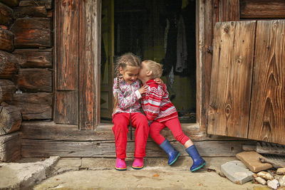 Full length of smiling girl sitting on wooden door