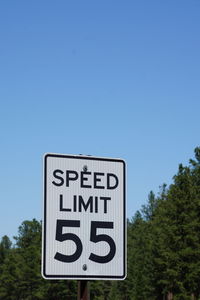 Low angle view of road sign against clear blue sky