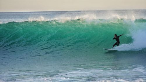 Man surfing in sea against sky