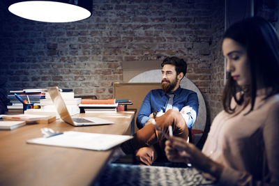 Businesswoman using tablet computer while sitting by colleague in conference room