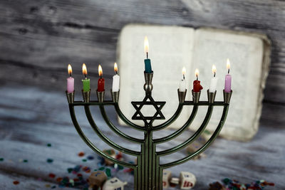 Close-up of candles in holder by bible on table