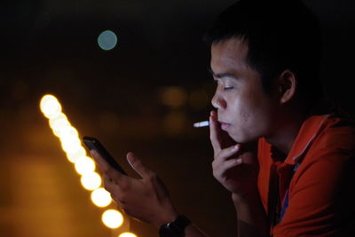 Portrait of young man smoking at night