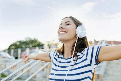 Happy young woman wearin headphones enjoying the summer