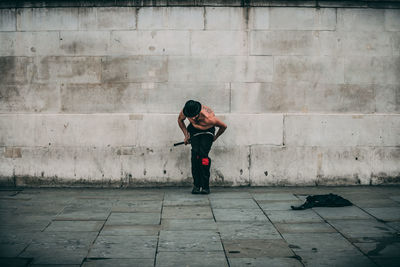 Full length side view of man standing against wall