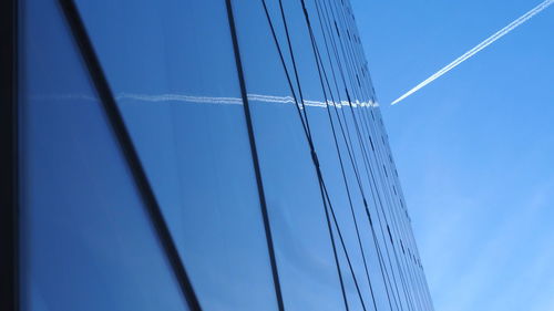 Low angle view of modern glass building against blue sky