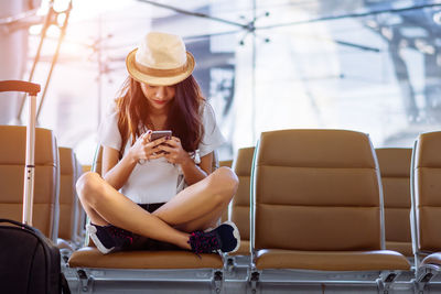 Young woman using mobile phone while sitting on seat