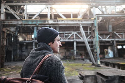 Young man wearing knit hat against abandoned building