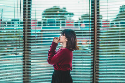 Young woman looking through window