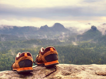 Brown orange hiking boots on rocks in front of mountain range. outdoor shoes