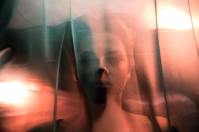 High angle portrait of woman lying on bed at home seen through fabric