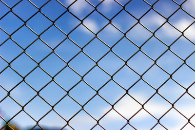 Full frame shot of chainlink fence against blue sky