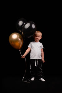 Portrait of cute boy standing against black background