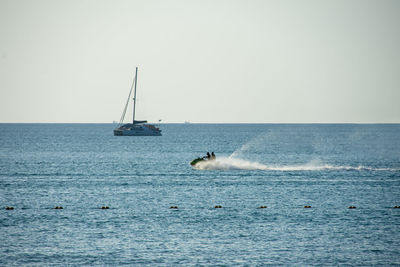 Sailboat sailing on sea against clear sky