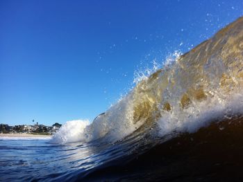 Close-up of waves splashing on beach against sky