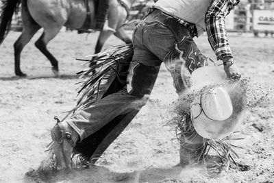 Low section of cowboy with hat walking on sand