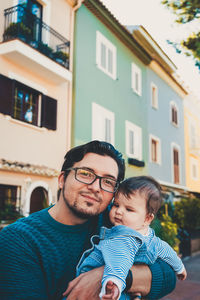 Portrait of father with daughter against building