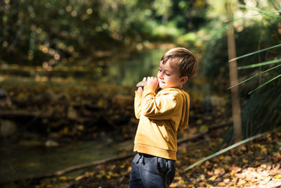Portrait of young woman standing against trees