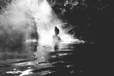 Silhouette woman swimming in lake at forest
