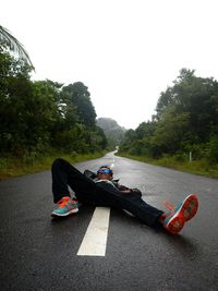 Man sitting on road against clear sky