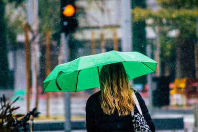 Rear view of woman with umbrella in rain