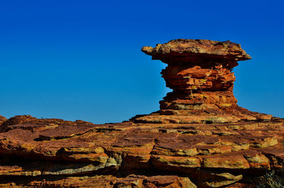 Low angle view of rock formation against clear blue sky