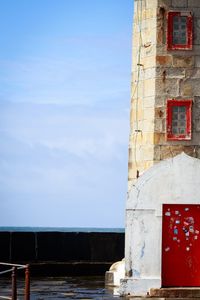 Old building by sea against sky