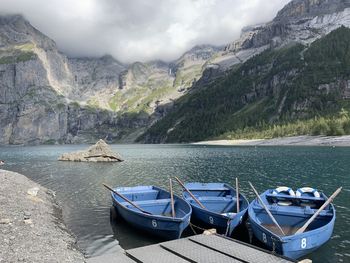 Boats moored on lake against mountains 