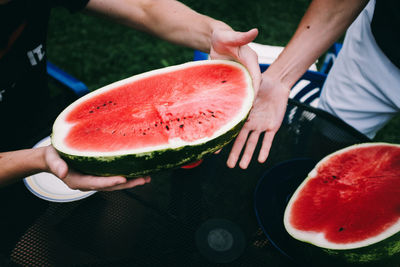 Midsection of people holding watermelon on table