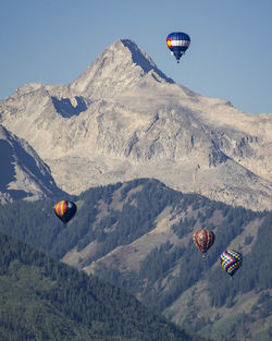 Hot air balloon flying over mountains against sky