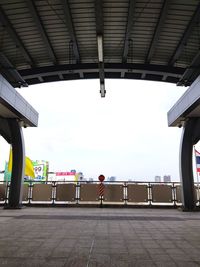 Rear view of people standing on railroad station platform against sky