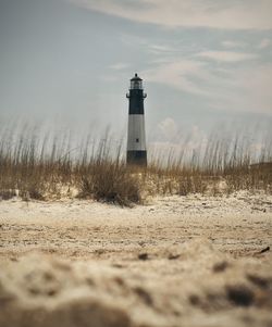 Lighthouse on field against sky