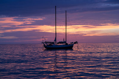 Boats in sea at sunset