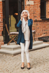 Full length of young woman standing against wall