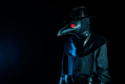 Midsection of person wearing mask against black background