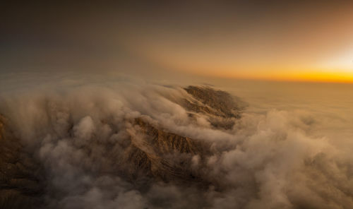 Aerial view of snowcapped mountains against sky during sunset