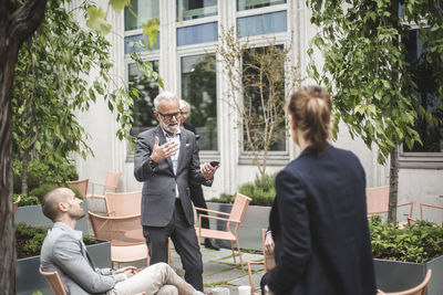 Senior businessman discussing business strategies with coworkers at office yard